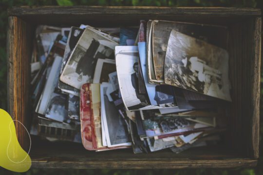 Stare fotografie ułożone w drewnianym pudełku. Symbol pracy z pamięcią w hipnozie