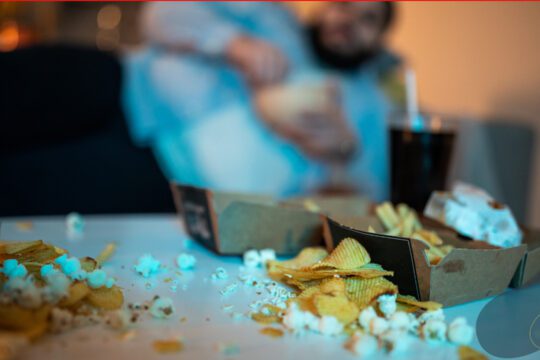 Jedzenie typu fast food rozsypane na stole jako symbol ucieczki od emocji i rozładowywania napięcia przez nawyki