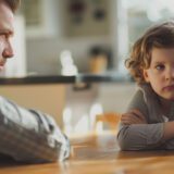 Małe dziecko odwrócone emocjonalnie od ojca podczas rozmowy przy stole