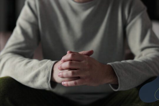 Mężczyzna siedzący ze splecionymi dłońmi - kryzys emocjonalny u mężczyzny i sygnały napięcia