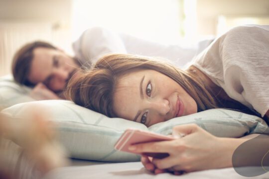 Męska zazdrość w związku - mężczyzna patrzy na partnerkę, która pisze na telefonie