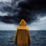 męski gniew przedstawiony symbolicznie jako mężczyzna stojący w deszczu przed nadchodzącą burzą”