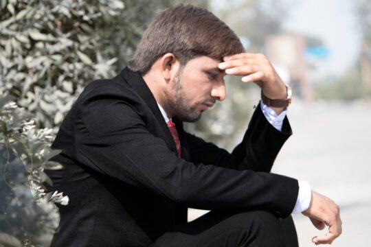 Mężczyzna w kryzysie finansowym siedzący w zamyśleniu, doświadczający napięcia i poczucia utraty kontroli
