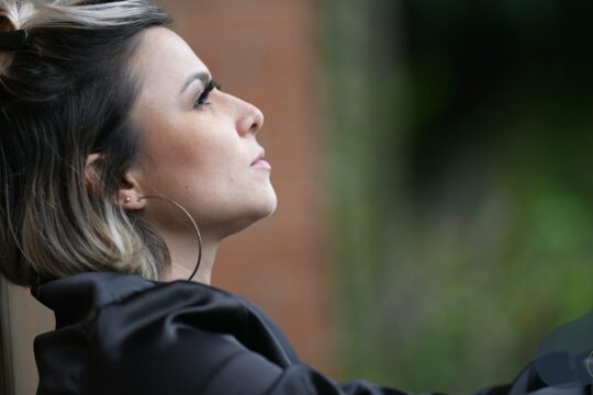 Kobieta w półprofilu oparta o ścianę, neutralna scena odnosząca się do wstydu jako emocji relacyjnej