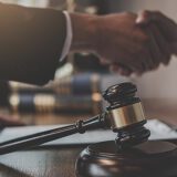 Spór bez sądu – uścisk dłoni nad dokumentem, młotek sędziowski w tle
