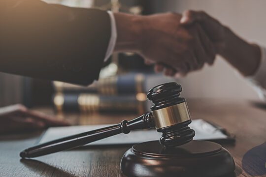 Spór bez sądu – uścisk dłoni nad dokumentem, młotek sędziowski w tle